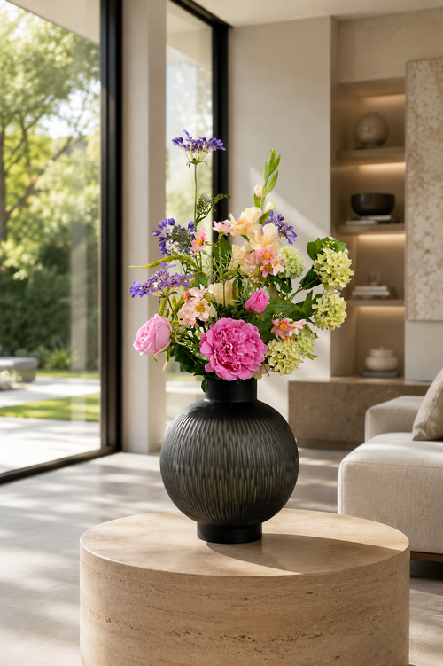 Zijden boeket Clara met roze bloemen en frisse groene accenten in donkere vaas van Fleurisant